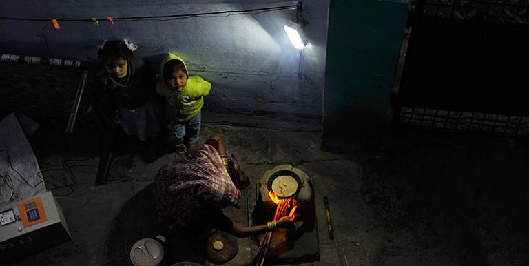 A woman makes chapatis under the light of a solar lamp in a village in Uttar Pradesh, India. Photo credit: ADB.
