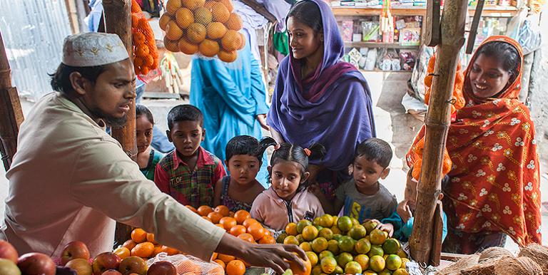 Mothers and their children shop at a fresh food market in the Bhashantek area of Dhaka city in Bangladesh, using money distributed through cash-based transfers. Photo credit: World Food Programme/Wahid Adnan.