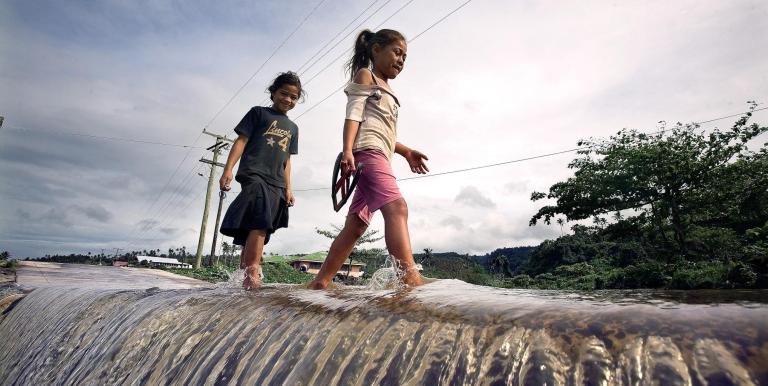 Children walk along a flooded road, underscoring the climate pressures driving Samoa’s investments in more resilient and reliable water systems. Photo credit: ADB.