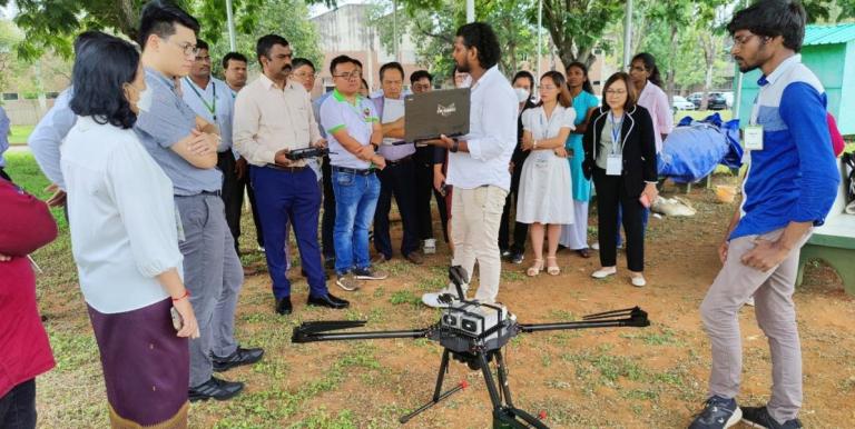 A staff member from the International Crops Research Institute for the Semi-Arid Tropics (ICRISAT) demonstrates the application of drones in advancing precision agriculture techniques. Photo credit: Landell Mills.